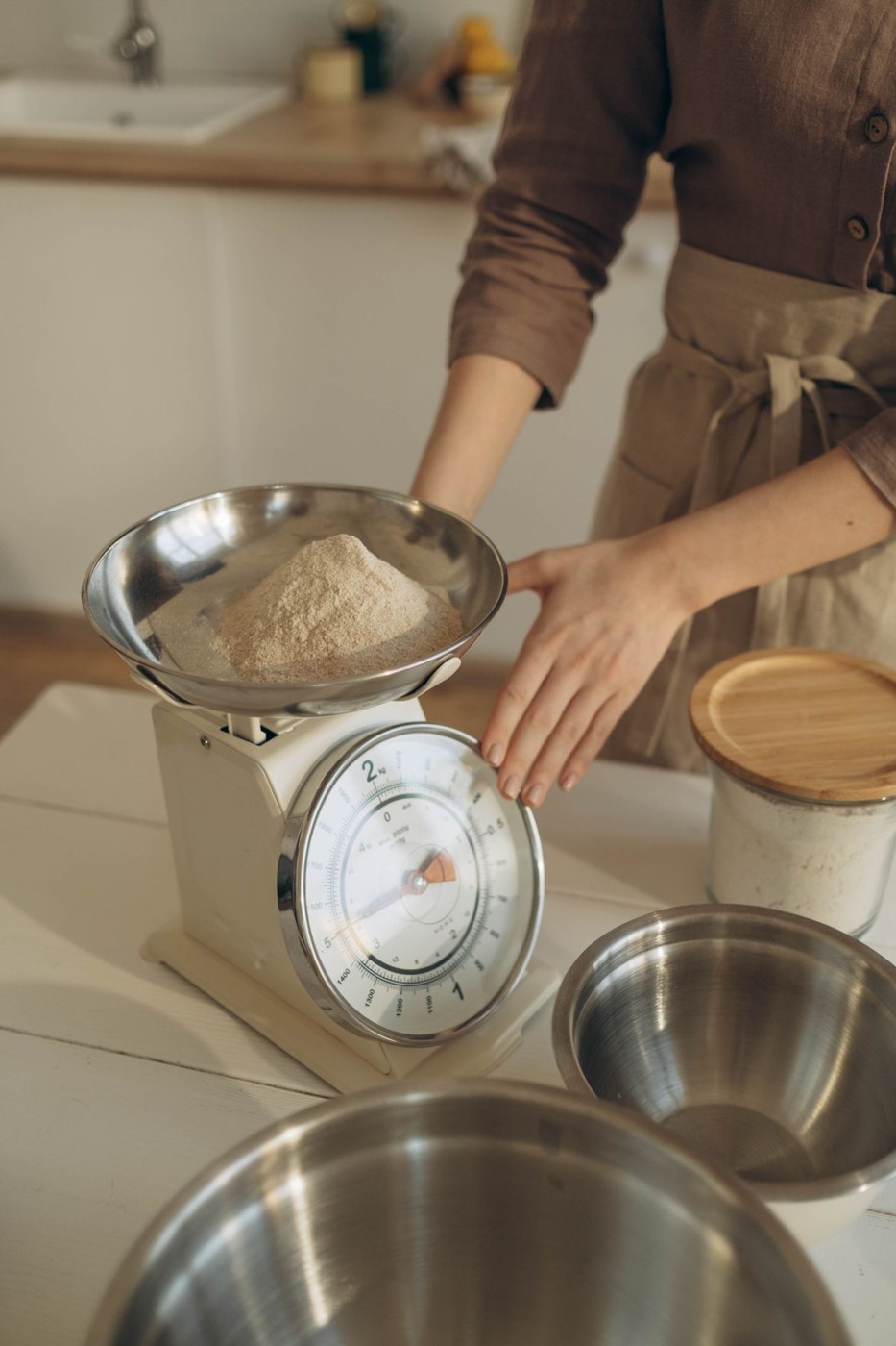 A bowl on a kitchen scale illustrates weighing an ingredient in its receiving container.